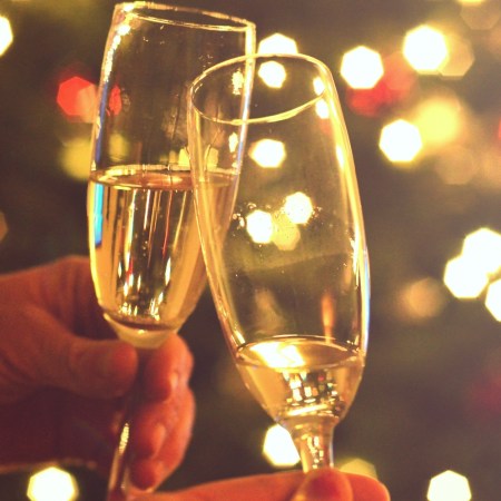 Close-up photo shows hands raising two glasses of champagne for a toast