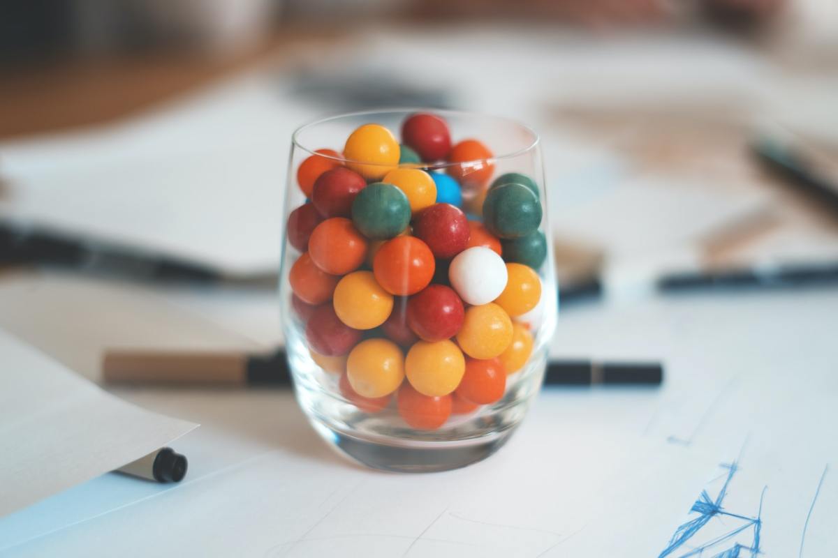 A jar of multi-colored chewing gum on a desk