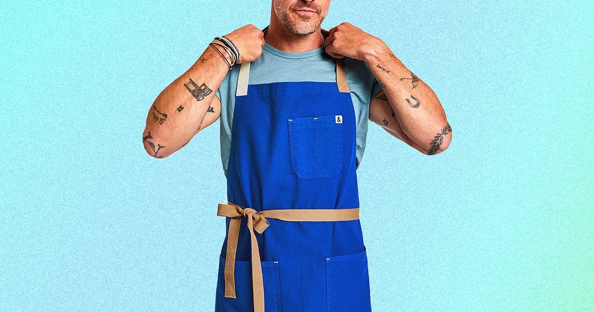 The Cobalt Blue kitchen apron from Hedley & Bennett on a tattooed man. The aprons are on sale this December 2021 and make for perfect Christmas and holiday presents.