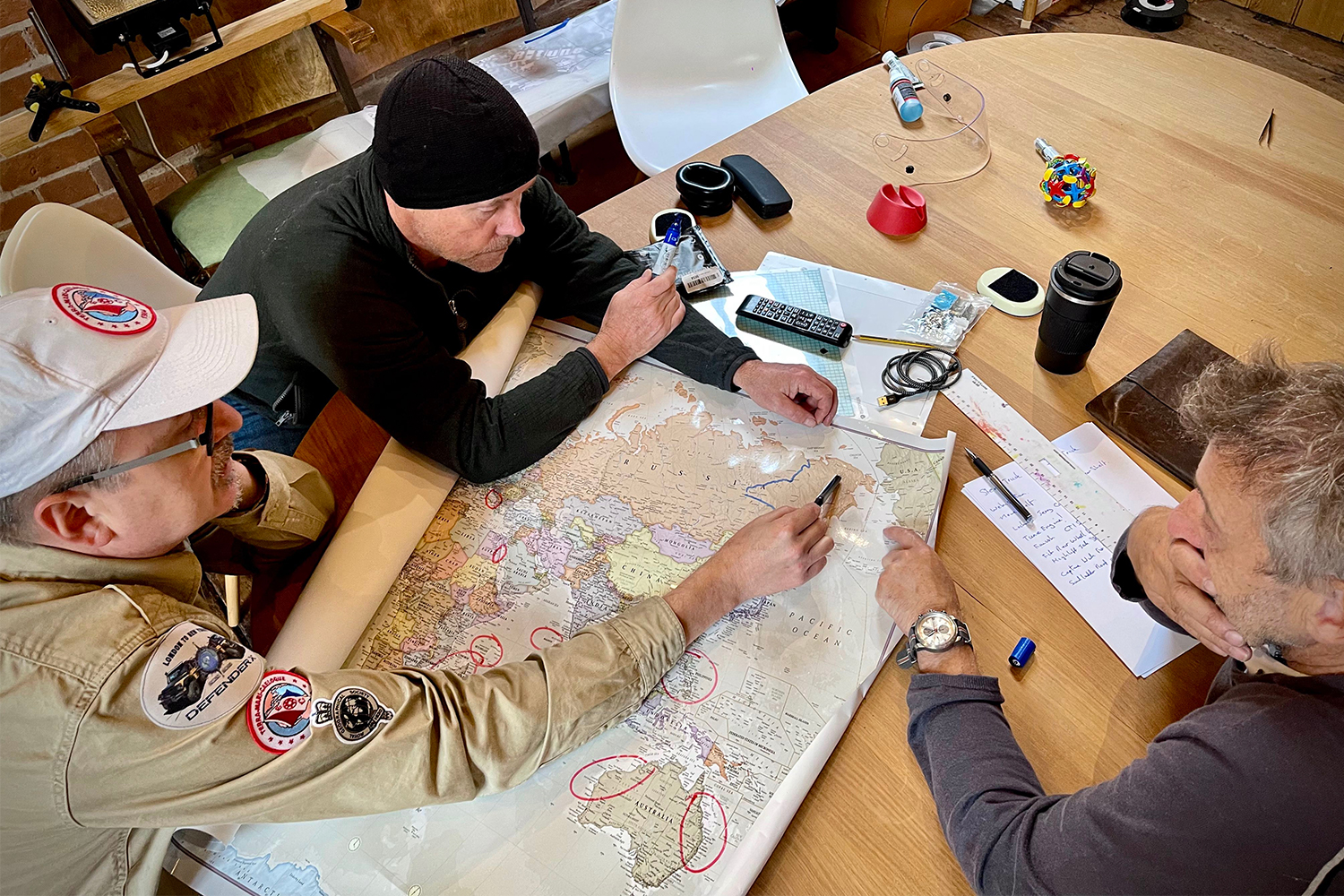 The DefenderX team studying global maps on a table, including Jeff Willner (left), Mikael Strandberg (center) and Steve Brooks