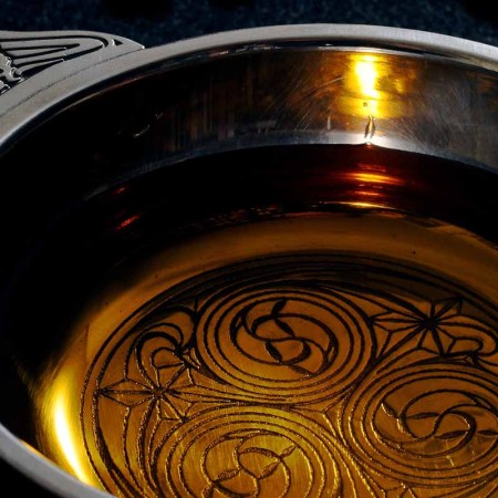 A traditional Scottish cup, a quaich, with a dram of single malt whiskey.