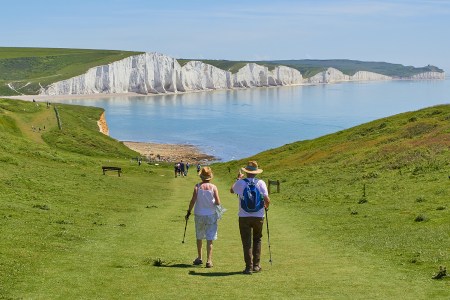 A retired couple walking down a grassy hill towards the water
