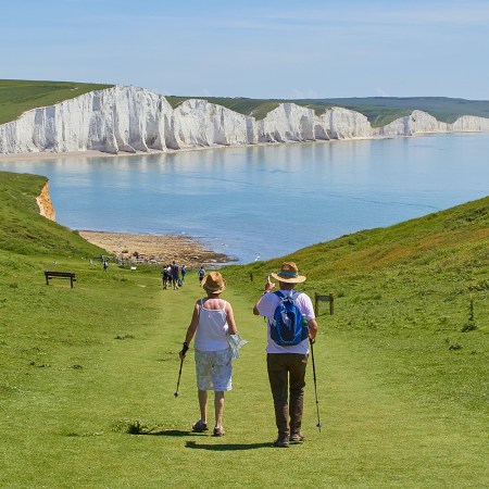 A retired couple walking down a grassy hill towards the water