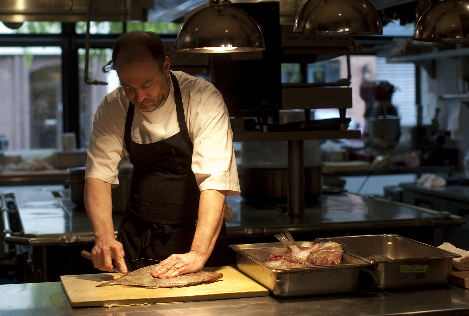 Chef Michael Tusk cuts fish in the kitchen at Cotogna