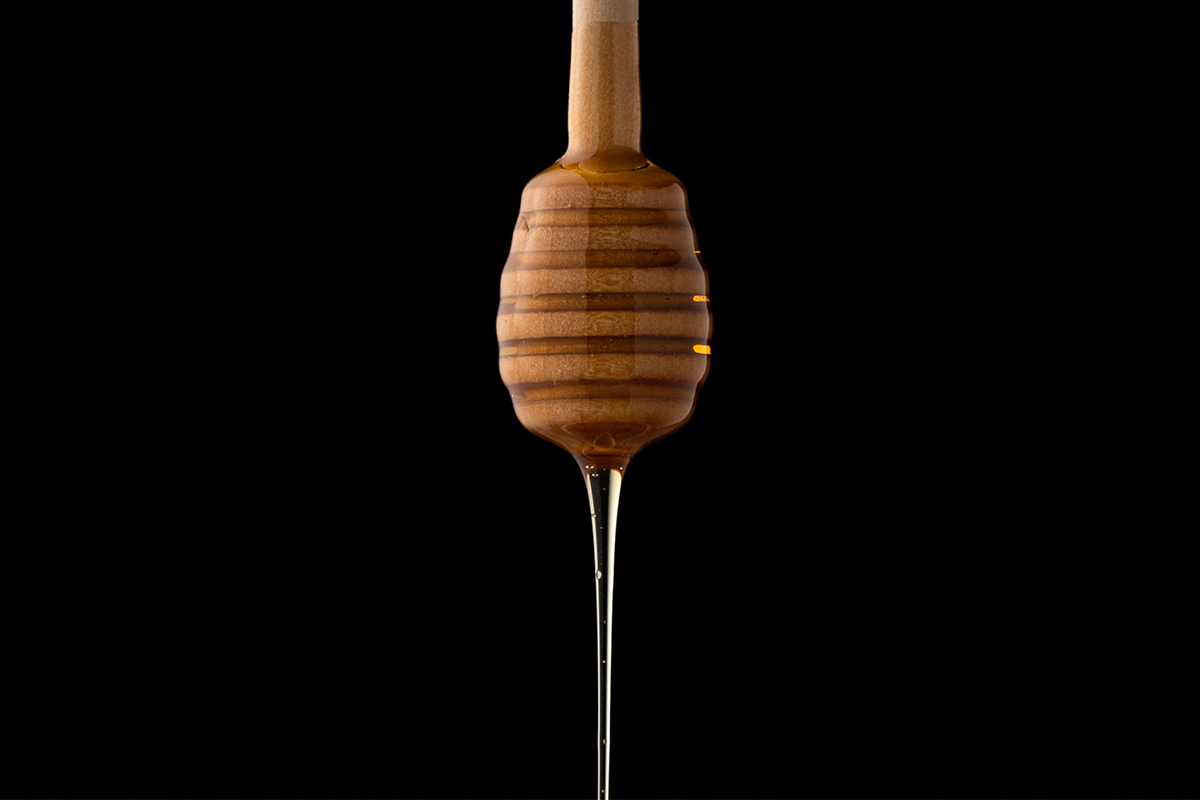 A honey dipper dripping with fresh honey. In 2022, consider replacing sugar with honey. Here's why.
