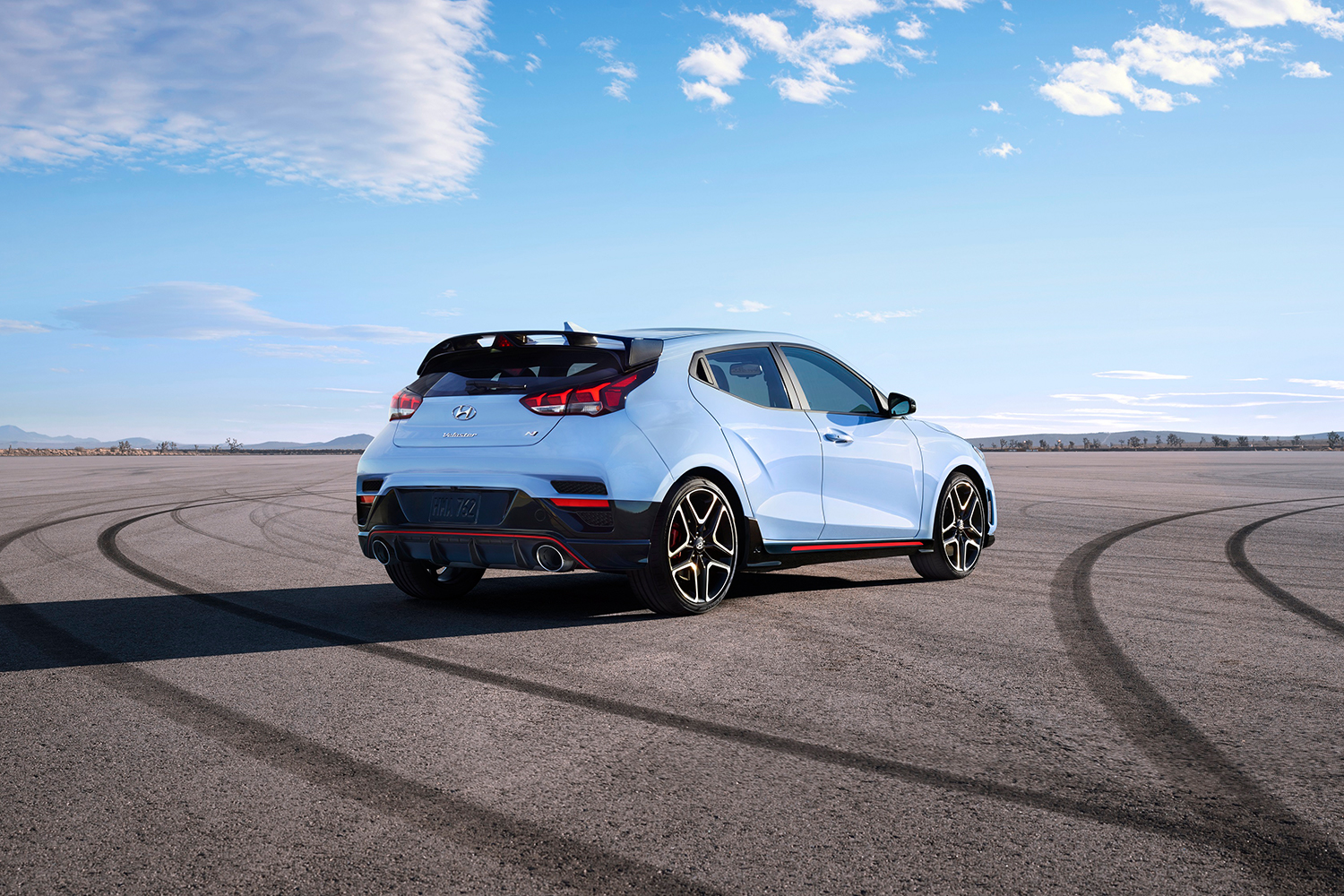 2022 Hyundai Veloster N sitting in the middle of a track during the day with clouds in the sky and tire tracks on the pavement