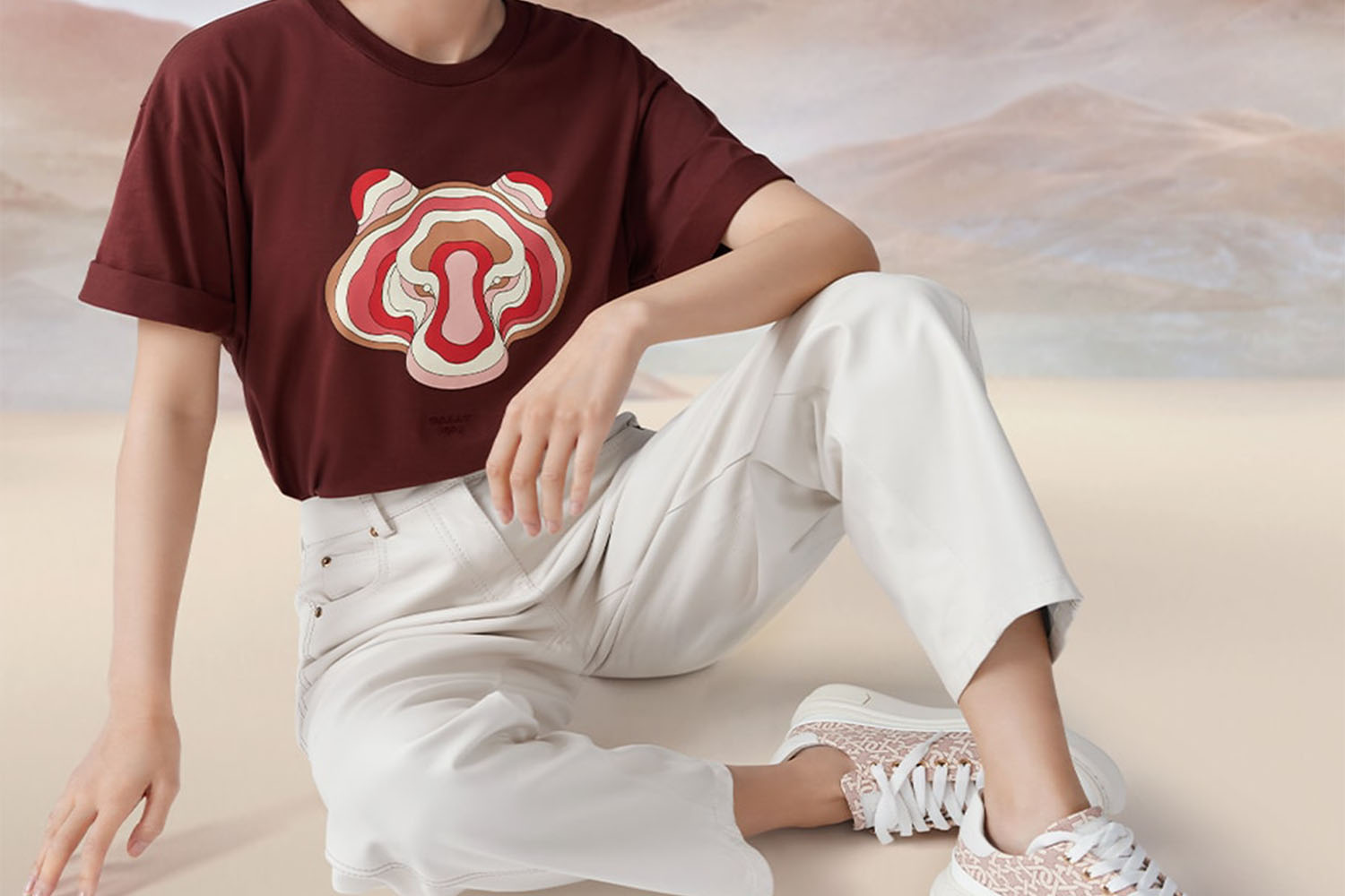 a model wearing white pants and a burgundy tee with the lunar New Years tiger on it