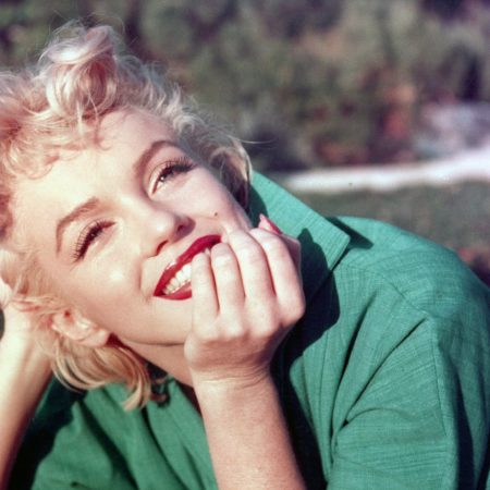 Marilyn Monroe poses for a portrait laying on the grass in 1954 in Palm Springs, California.
