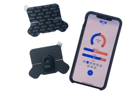 An iPhone with an app on display beside photos of two wearable patches