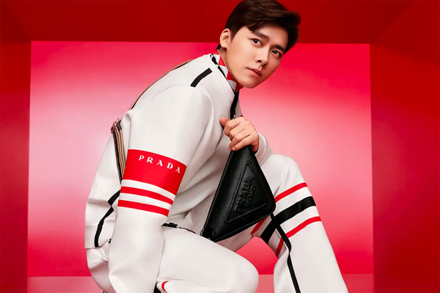 a kneeling model in white with red striped outfit from Prada