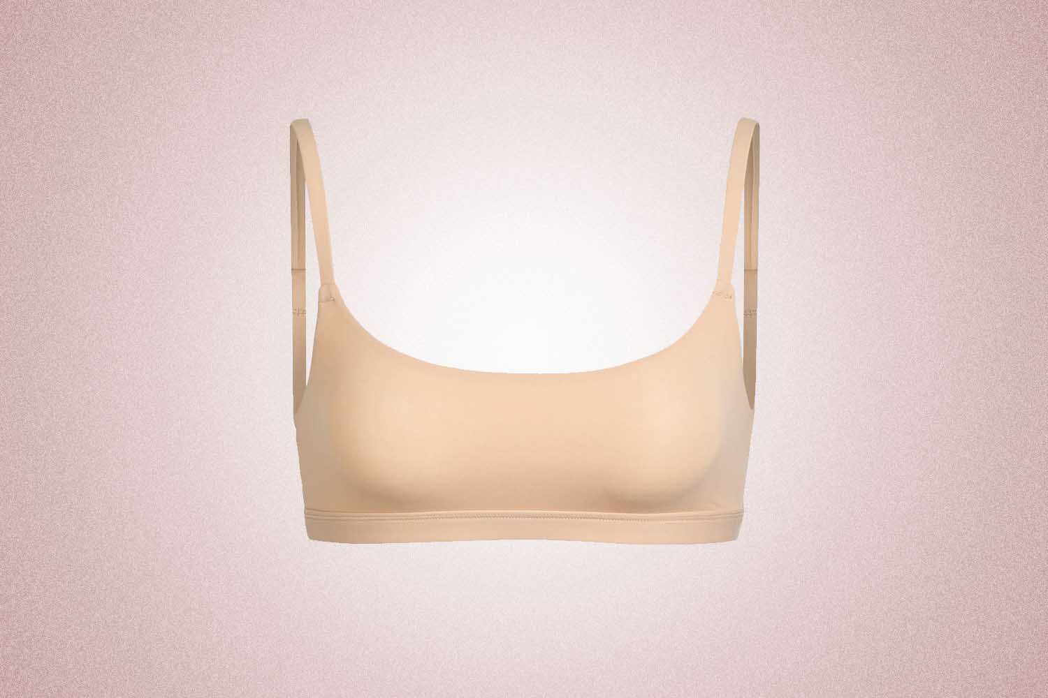 A tan scoop neck bra from Kim Kardashian's brand Skims, a perfect Valentine's Day gift, on a pink background. 