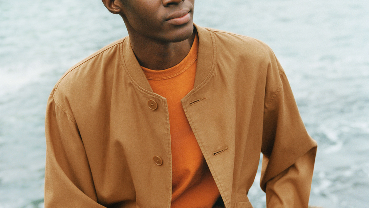 A model in an organ shirt and tan jacket