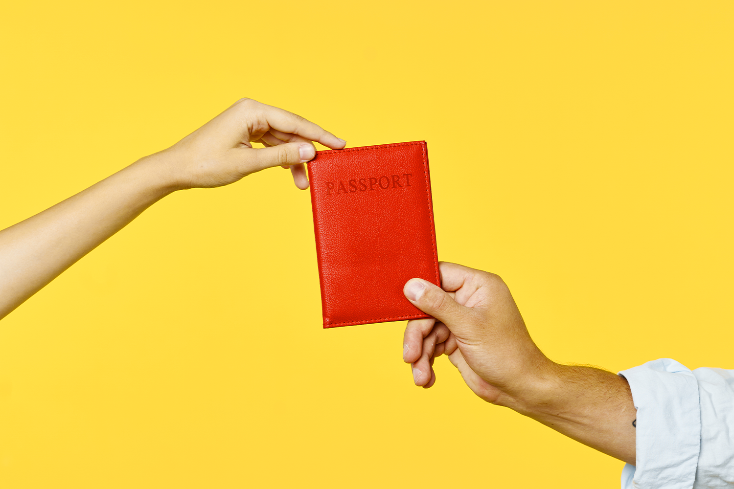 Two hands holding a passport against a yellow background. What's the most powerful passport in 2023? The list was just released.