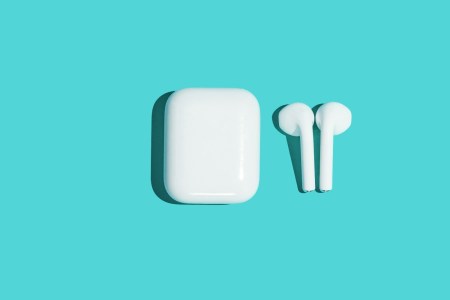 Wireless white headphones on turquoise background.