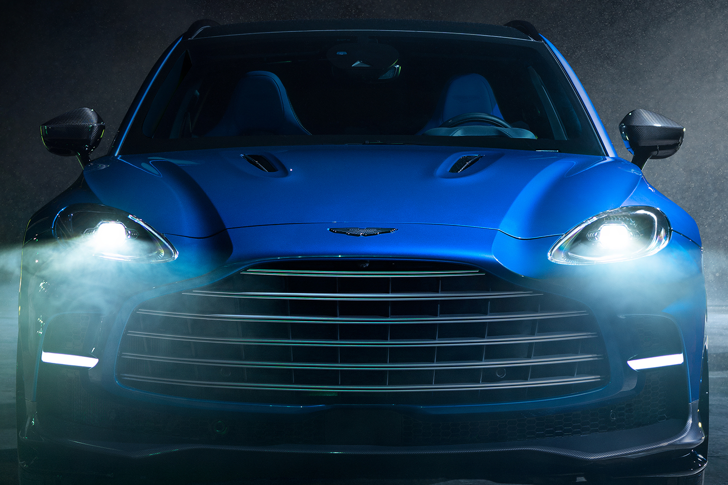 The new high-performance Aston Martin DBX707 SUV in blue with its headlights on. The SUV debuted on February 1, 2022 and will be available in Q2 this year.