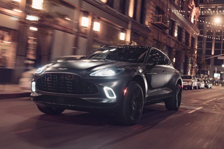 The Aston Martin DBX SUV driving at night. The British automaker just announced a new high-performance version of the DBX, which will be unveiled in February 2022.