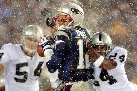 Tom Brady takes a hit from Charles Woodson of the Oakland Raiders in a 2002 AFC playoff game