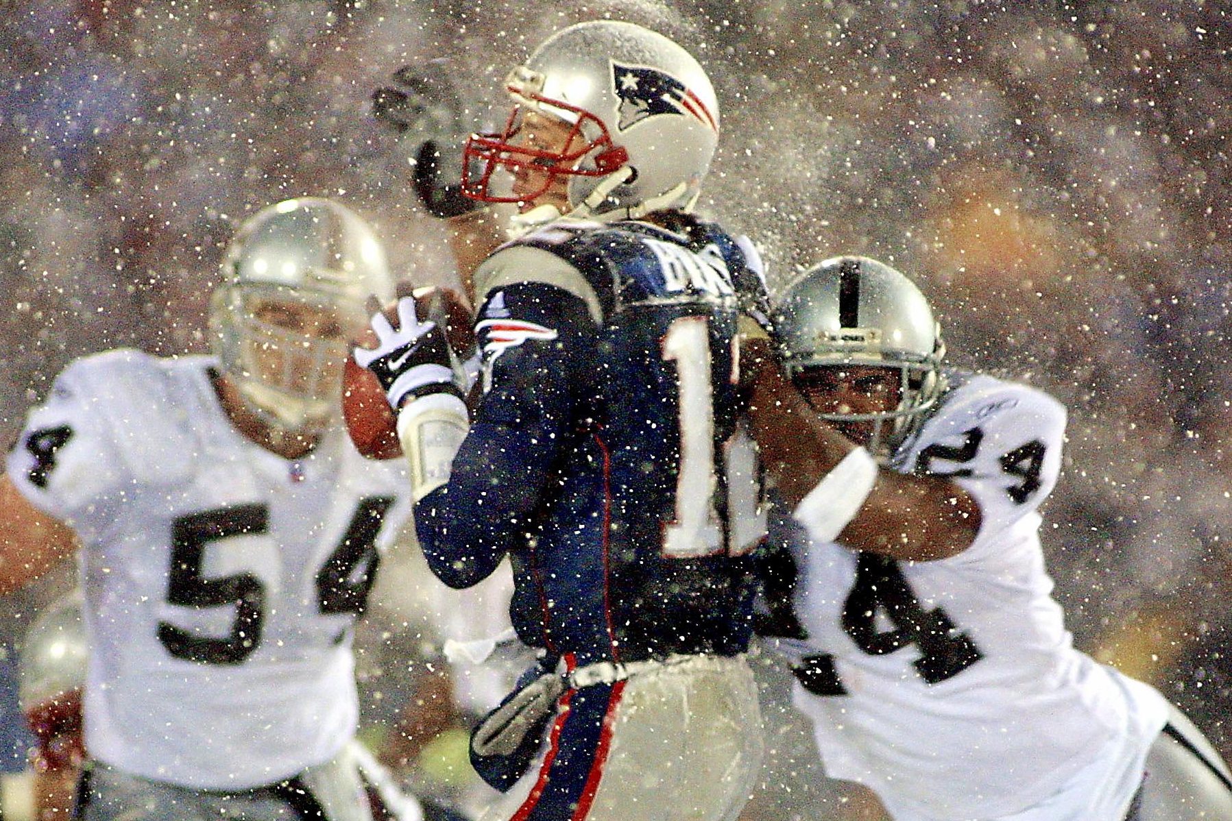 Tom Brady takes a hit from Charles Woodson on a pass attempt in their AFC playoff game in 2002