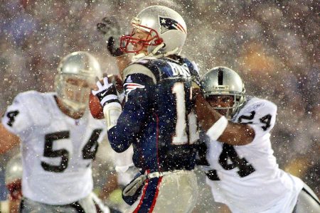 Tom Brady takes a hit from Charles Woodson on a pass attempt in their AFC playoff game in 2002