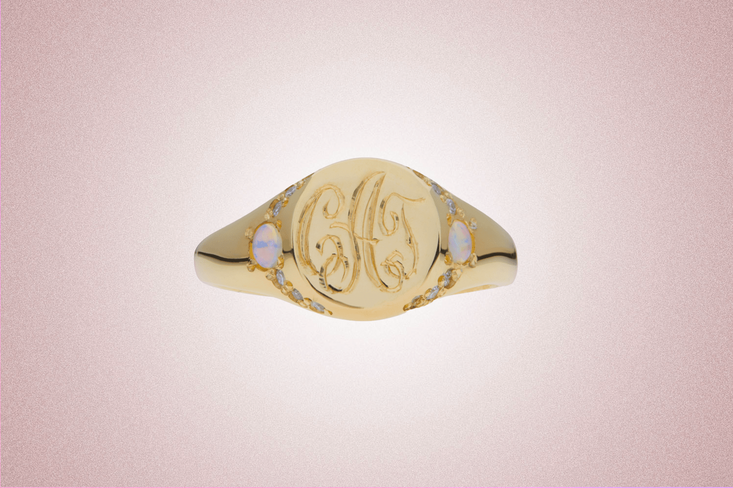 A gold signet ring set with opals and diamonds on either side from Catbird, a perfect Valentine’s Day gift for 2022, on a pink background.