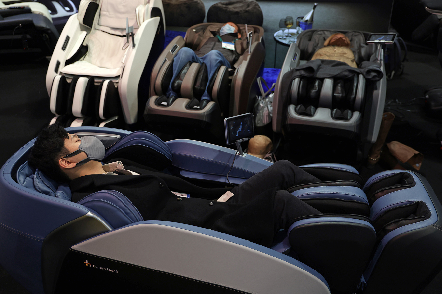 Attendees try out massage chairs at the Human Touch booth at CES 2022 at the Las Vegas Convention Center