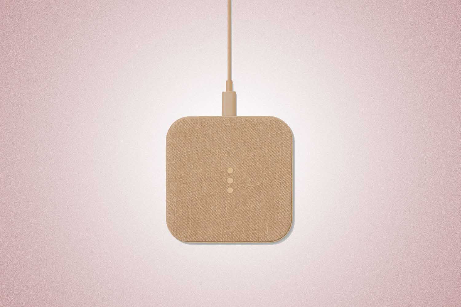 A tan wireless charging station from Courant, a perfect Valentine’s Day gift for 2022, on a pink background.