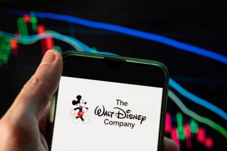 The Walt Disney Company text and Mickey Mouse character on a smartphone. Disney recently patented virtual reality, metaverse adjacent tech for their theme parks.