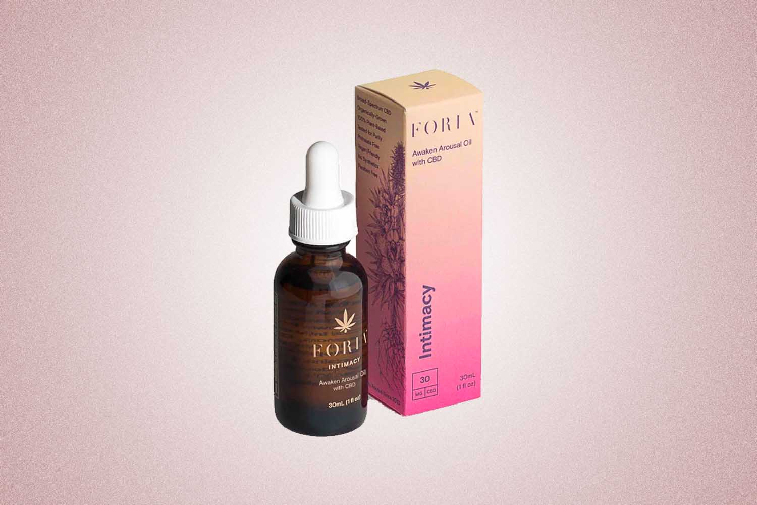 A tincture of Foria's Awaken Arousal Pil with CBD next to a pink box, a perfect Valentine's Day gift, on a pink background. 