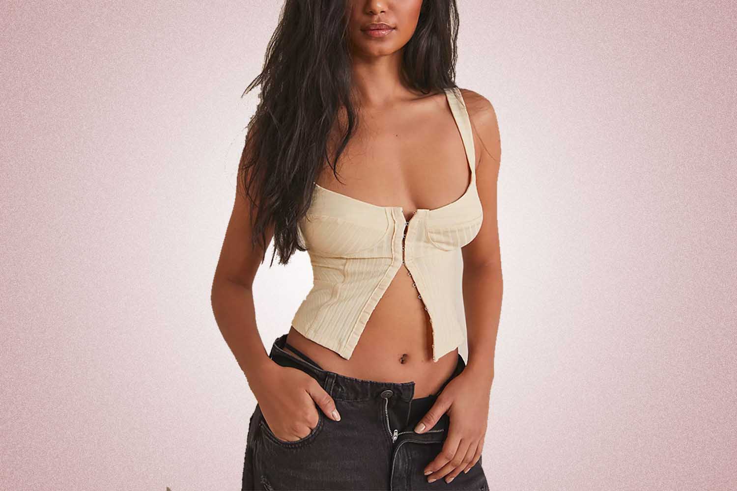 A tan corset cami from Free People, a perfect Valentine’s Day gift for 2022, on a pink background.