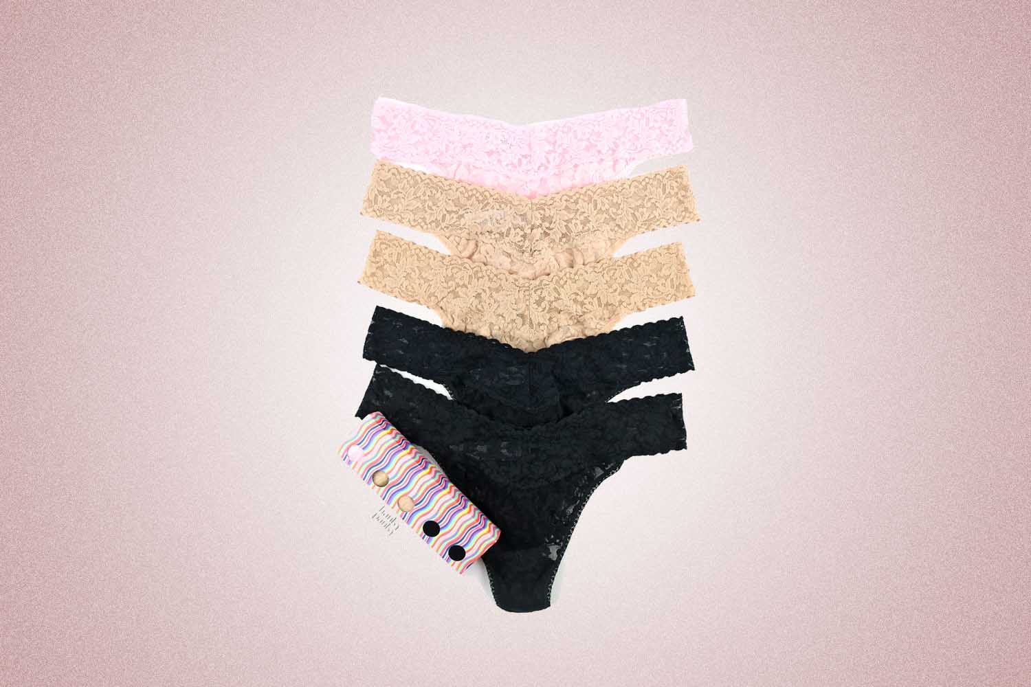 Five lace thongs from Hanky Panky stacked on top of each other, a perfect Valentine’s Day gift for 2022, on a pink background.