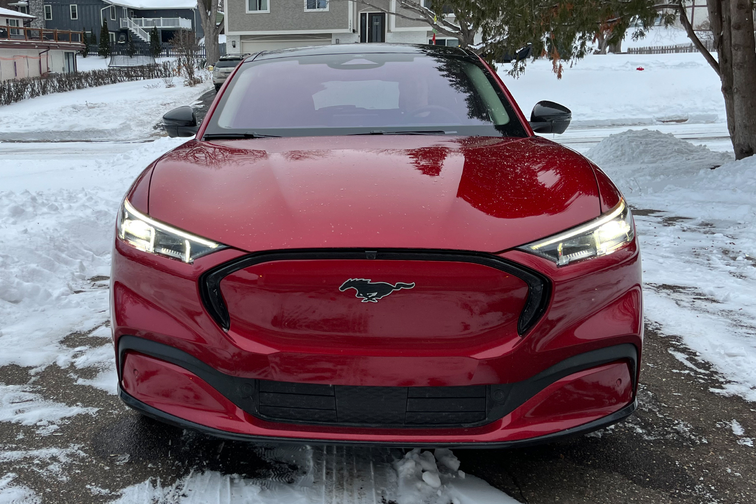 A 2021 Ford Mustang Mach-E Premium AWD electric crossover in red sitting in a Minnesota driveway. I tested its cold-weather stamina.