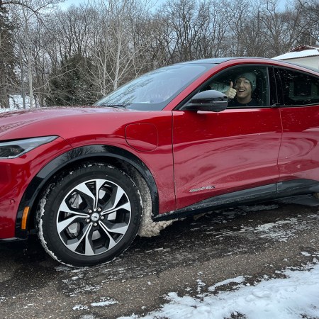 A red 2021 Ford Mustang Mach-E, an electric crossover SUV, in the driveway of a Minnesota home. I idled the EV for 12 hours in for a cold-weather test.
