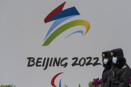 Security officers walk by a billboard for the Beijing 2022 Winter Olympics