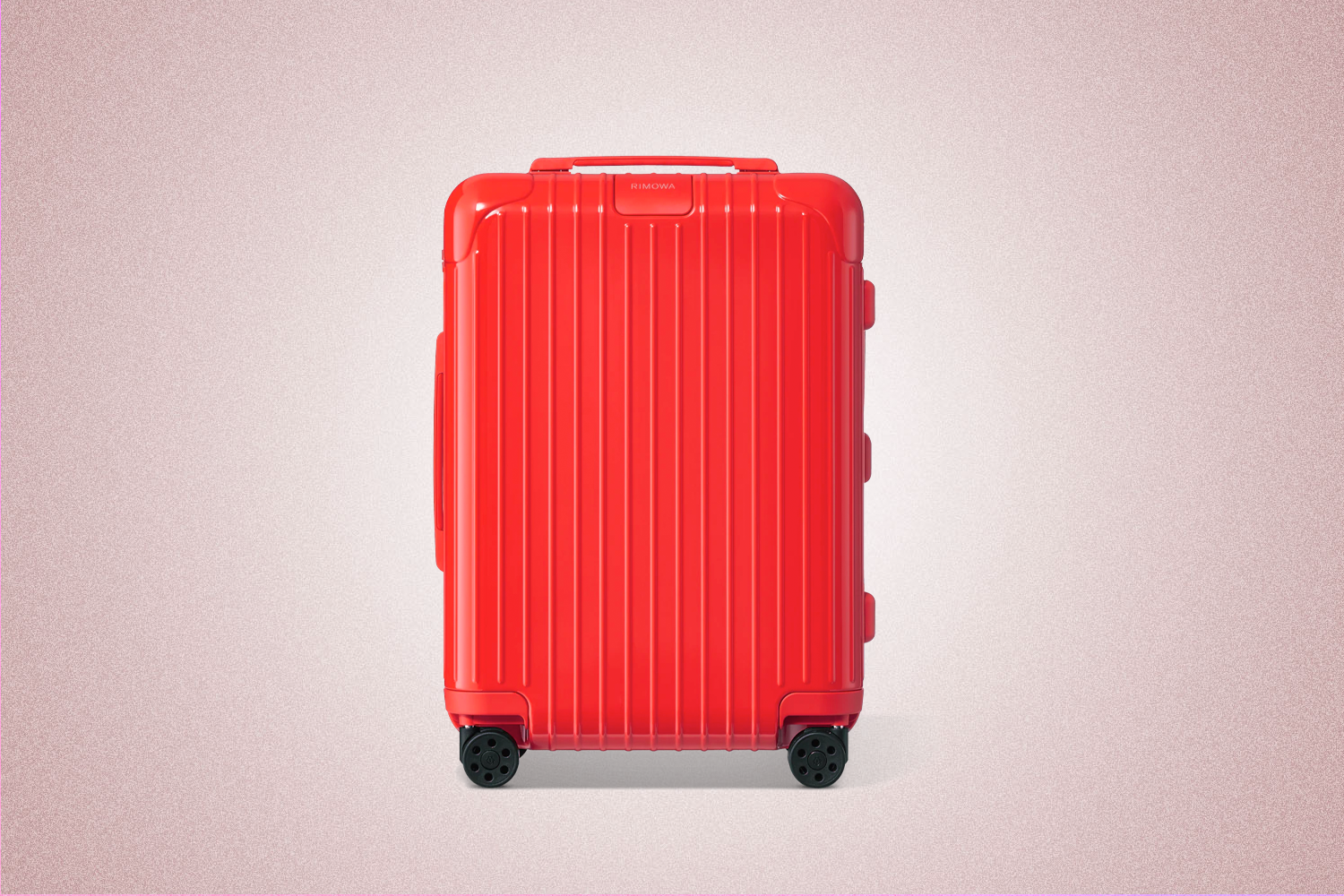 A red polycarbonate suitcase from Rimowa, a perfect Valentine’s Day gift for 2022, on a pink background.
