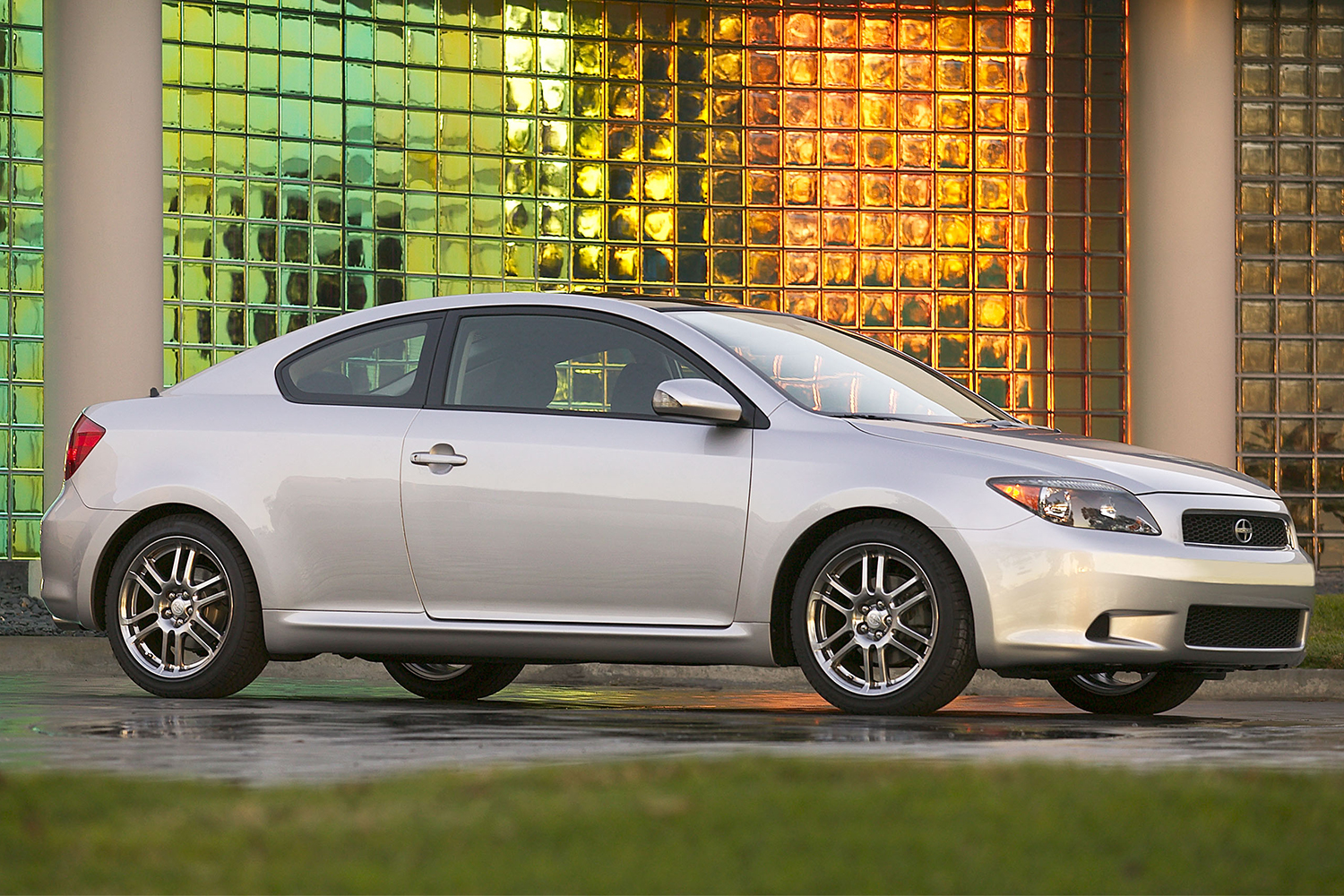 The 2005 Scion tC compact car. Here the coupe is pictured sitting in front of a colored glass wall.