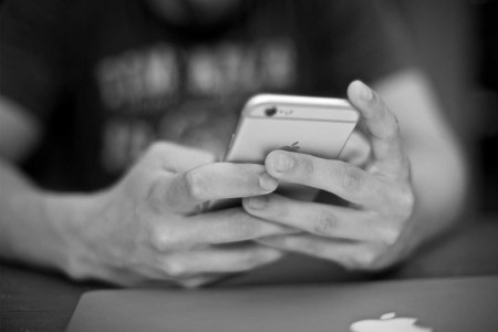 A black and white photo of hands holding an iPhone.