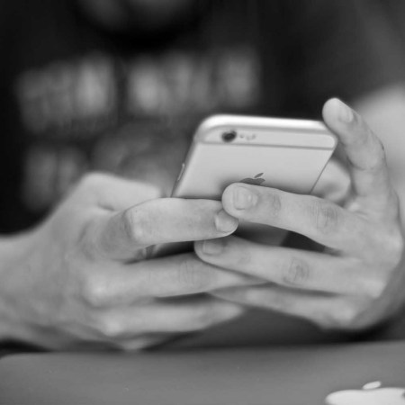 A black and white photo of hands holding an iPhone.