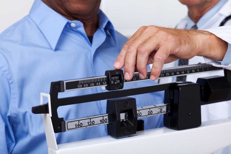 A photo of a doctor checking weight of patient. A new article suggests you can probably skip the weigh-in.