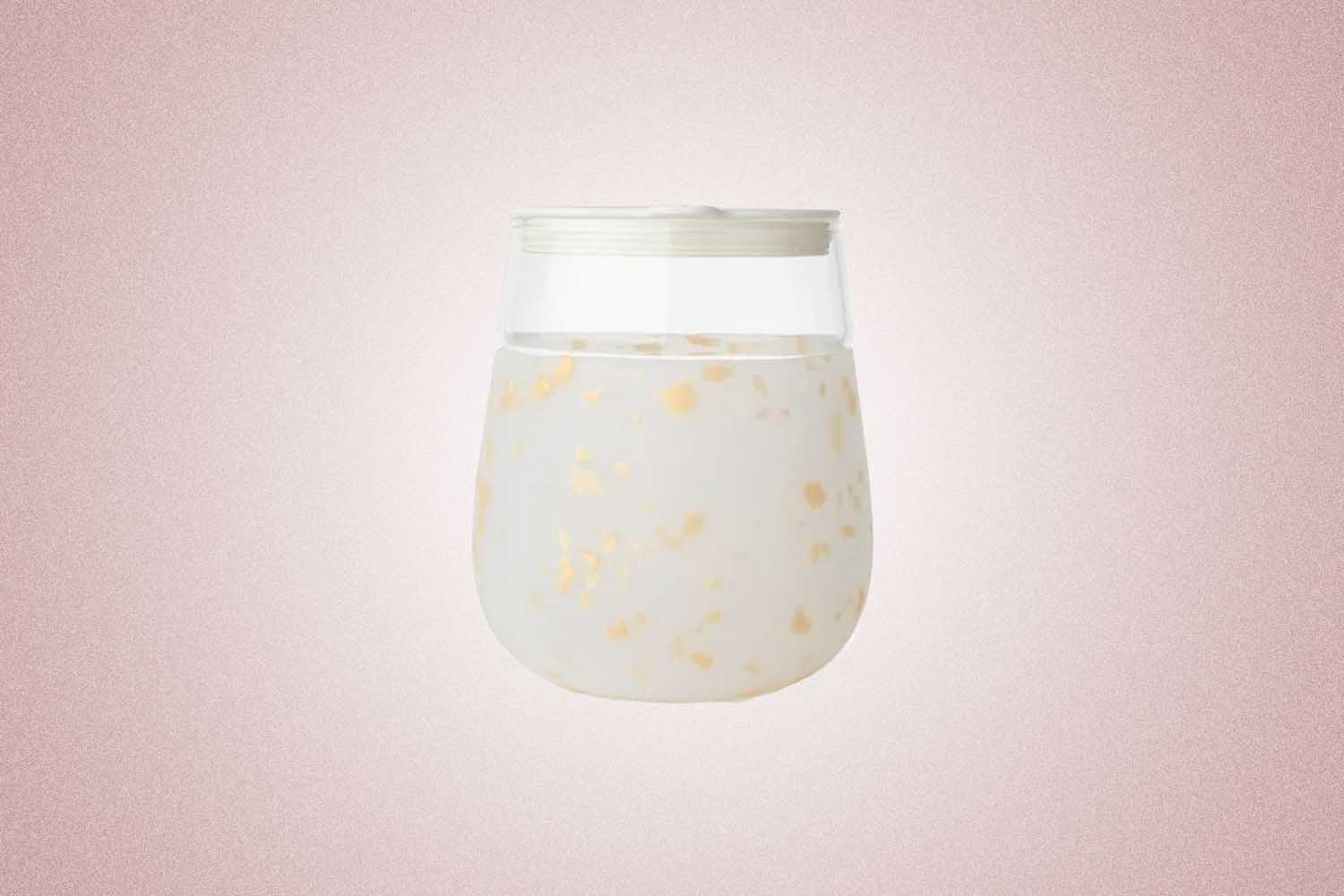 A white reusable wine glass with a speckled gold pattern from W&P, a perfect Valentine’s Day gift for 2022, on a pink background.