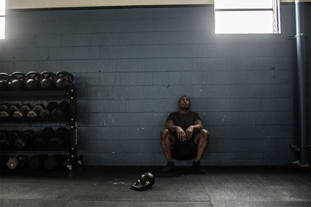 A man resting against the wall in a gym. New studies indicate that people with long COVID have a hard time exercising.