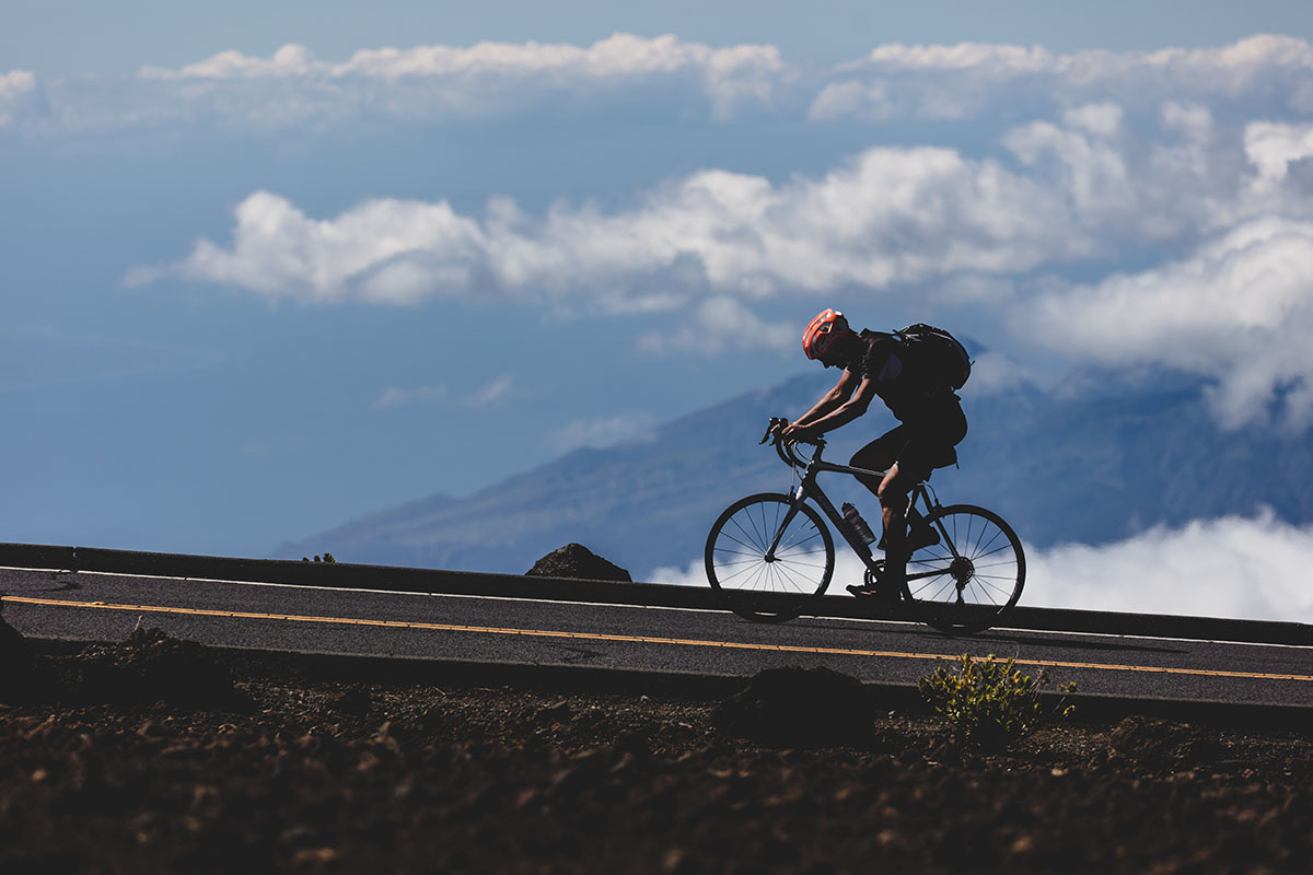 A man biking up a hill with mountains in the background
