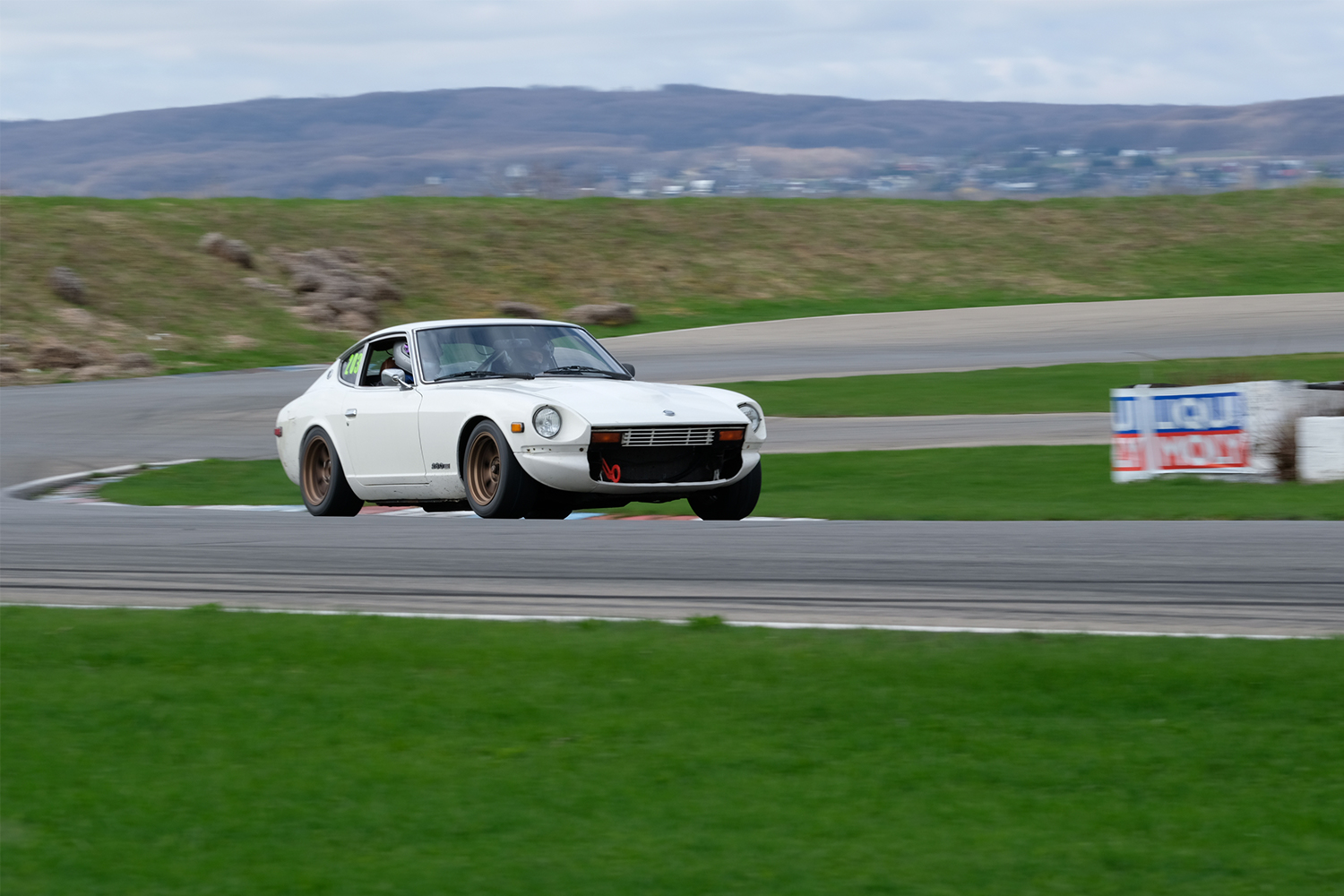The author driving his white 1978 Datsun 280Z car on a racetrack. He bought the classic car to drive on track days.