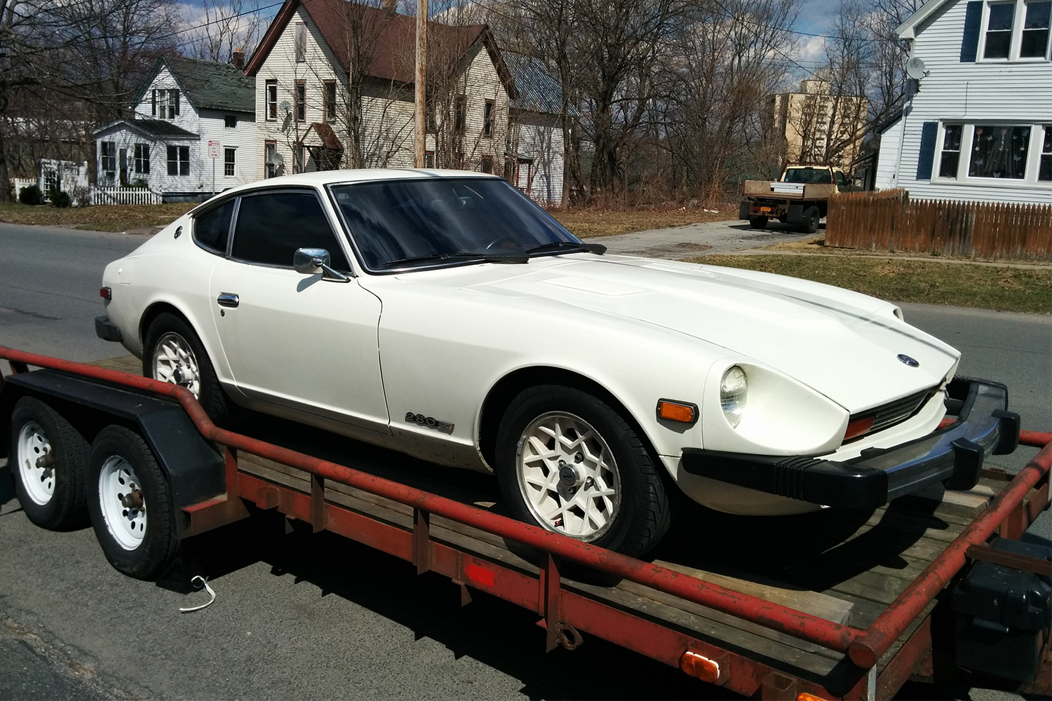 A white 1978 Datsun 280Z with snowflake wheels and a giant bumper on a trailer. We talk about what it's like to own the classic '70s sports car.