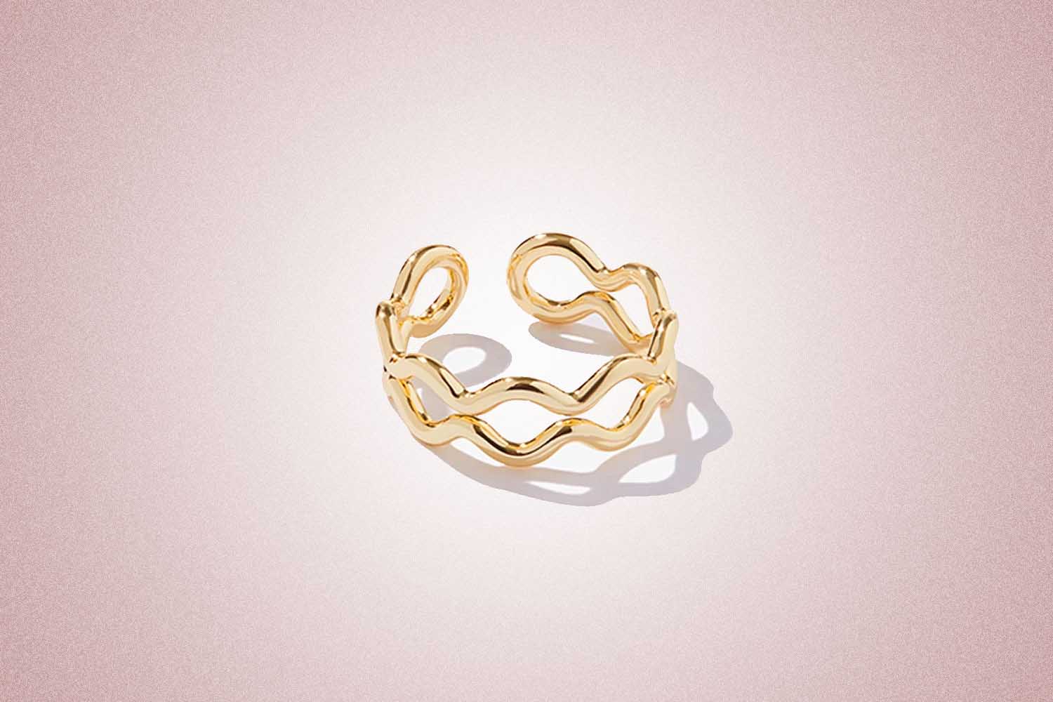 A wavy gold ring, a perfect valentine's day gift, on a pink background. 
