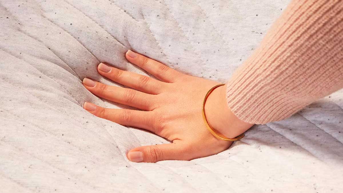 A hand pressing down on a Casper mattress