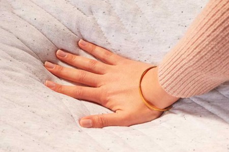 A hand pressing down on a Casper mattress