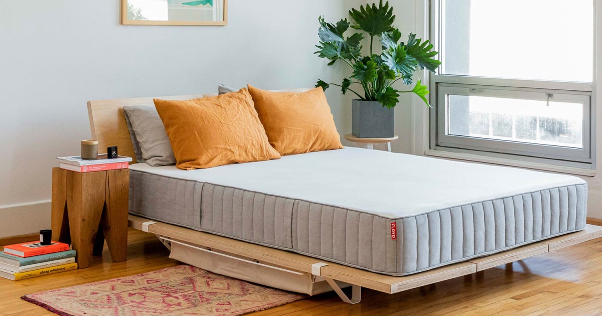 a mattress on a nice wooden frame in a minimal room