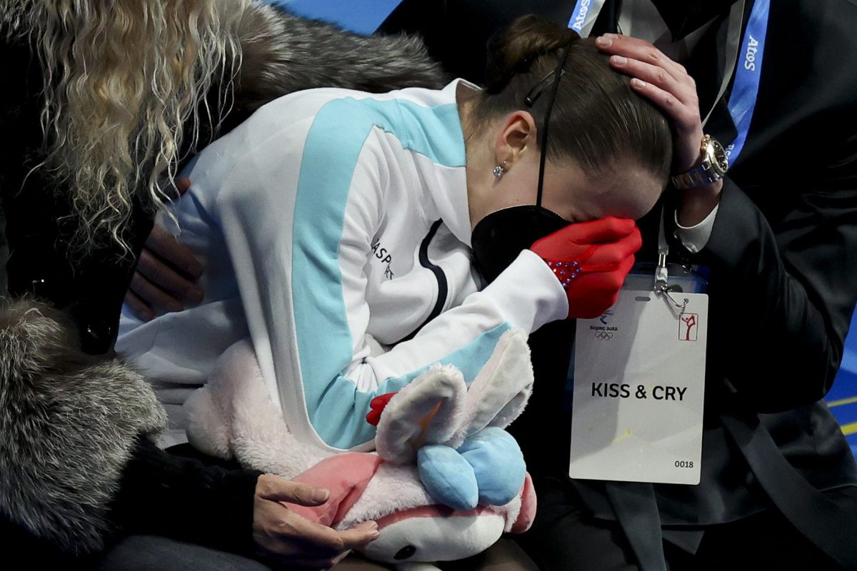 Kamila Valieva of Russia reacts to her score with coach Eteri Tutberidze (L) and Daniil Gleikhengauz (R) at Capital Indoor Stadium on February 17, 2022 in Beijing, China.