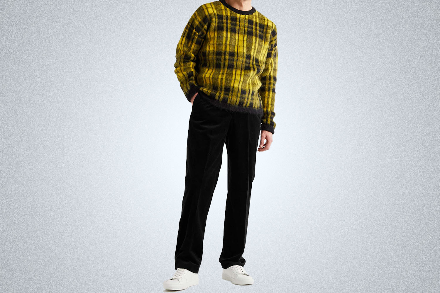 a model in a yellowfins checked sweater and black corduroys