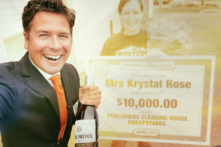 Howie Guja, part of the Publishers Clearing House Prize Patrol, holds a bottle of Champagne while standing next to Krystal Rose, a sweepstakes winner holding an oversized check for $10,000